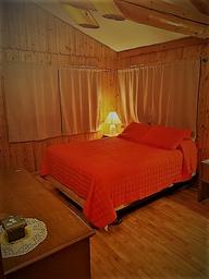 Main bedroom with wood paneling and bed — lodging page photograph depicting on-site sleeping accommodations (helps illustrate lodging options).