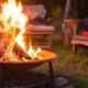 Atmospheric photo of a fire pit with Adirondack chairs on grassy ground — illustrates typical campground amenities and is used as a background image on the site.