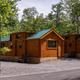 Exterior view of on-site log-style cabins grouped on gravel pads with access road and trees — useful for lodging/cabin listing on the property pages.