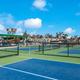 Multiple fenced courts (pickleball/tennis) with RVs visible beyond — highlights on-site recreation facilities featured on the property page.