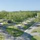 Overhead view of a campground with RVs, trees, pathways, and picnic tables on a sunny day.