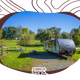 Framed image of an RV parked at a gravel site with picnic table and open lawn — directly represents RV sites and matches the RV Sites section on the accommodations page.