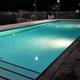 Night view of the resort swimming pool with surrounding fence and chairs — clearly a campground facility. Source from the home page social image suggests this is a property photo of French Camp RV Park's pool area.