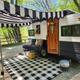 Decorated travel trailer/RV site with awning and gravel pad visible — useful to show the RV campsite setup and ambiance.