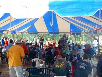 Large tent/pavilion event photo with many campers seated — depicts the campground’s event/assembly space and seasonal community activities (from Seasonal Camping page).