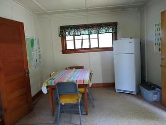 A refrigerator next to a window and dining room table.