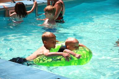 Outdoor heated pool with children playing — shows the campground’s pool amenity referenced in the recreation/activities section of the site.