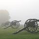 Four civil war cannons along a green foggy field.