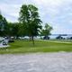 Panoramic view showing RV sites, open lawn, and cabins along the shoreline — strong overview of the property layout and scale (suitable as an aerial/overview substitute).