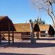 Row of rustic log cabins under tall trees at USA RV Park in Gallup, New Mexico