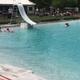 Clear photo of the campground swimming pool with slide and surrounding lawn/chairs — shows on-site amenity; appears on site media for the park's pool.