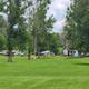 Panoramic view of several RVs parked across a grassy field with trees — good depiction of RV sites and spacing from the campground's gallery.