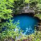 The bright blue water of Round Spring surrounded by greenery