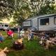 Evening scene of campers gathered around a campfire with RVs in background — highlights community atmosphere and on-site firepit areas (from the campground's photo gallery).