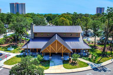 Clear photo of the main clubhouse / facility building on the property with surrounding grounds and distant beach visible — useful facility image.