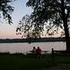People at a picnic table at sunset overlooking the river.