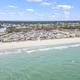 Aerial photo showing the campground strip along the beach and nearby facilities; useful as an overview of site layout and proximity to shore (source page: testimonials).