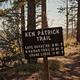 Ken Patrick Trail sign in a pine forest, listing Cape Royal and Grizzly Ridge trail distances.