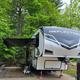 Clear photo of a seasonal full-hookup RV parked at a campsite with picnic table and forested background; appears on the site’s Seasonal Rentals page illustrating on-site RV sites and amenities.