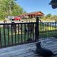 View from a porch toward a large pavilion/building and resort grounds with decorative landscaping and RVs — illustrates guest facilities and the campground atmosphere (sourced from homepage/accommodations images).