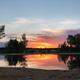 Sunset reflected on the swimming pond with visible campground area beyond the beach — attractive scenery shot that illustrates evening atmosphere at the pond (matches ‘Sunset on Haven Pond’ gallery image).
