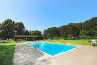 Outdoor swimming pool with surrounding lawn and fence — highlights on-site recreation facility. Source page: 'Pool.jpeg' on homepage.