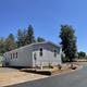 Exterior shot of a mobile home with surrounding road/landscape — shows placement and street layout within the park (matches listings on the property page).