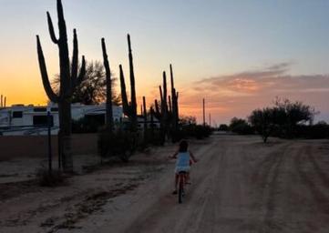 Dirt trail view with RVs and a cyclist at sunset — shows campground roads, RV sites and surrounding desert scenery (file Trails-outside-around-park-400x284.jpg).
