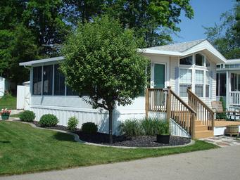 Park model / cabin exterior photograph showing a furnished seasonal unit and landscaping — good representation of on-site cabin/park-model lodging; appears on the property’s site as accommodation imagery.