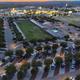 Twilight aerial showing the full resort layout, rows of paved RV sites, central green area and surrounding roads — matches RV Sites page twilight drone image and establishes overall property footprint.