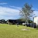 Clear daytime photograph showing multiple RVs parked on grassy, full-hookup sites with visible utility pedestals and site layout — good overview of the resort’s RV pitches (from home page).
