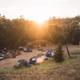 Sunset view of a tent camping area with multiple tents and communal fire/picnic area — illustrates tent camping and the campground’s scenic setting at dusk.