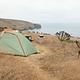 Tent sitting in dried grass on a ocean bluff overlooking the coastline.