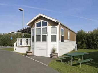 Close exterior image of an individual cabin unit with steps, picnic table and lawn — useful to illustrate single-site cabin amenities on the property.