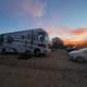 Another wide dusk shot showing a large motorhome on a gravel pad and nearby car — useful for illustrating RV pitch size and surface. Sourced from the property homepage (Granberry Gardens LLC).