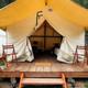 Front view of a single tent on its raised wooden platform with steps and porch — useful for showing guest accommodation entrance and tent details.