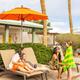 Pool-side scene with lounge chairs, umbrella and palm trees — depicts the campground’s pool/recreation area and on-site amenities (from the campground waystostay photos).