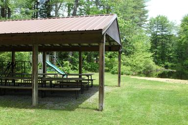 Covered pavilion / picnic shelter beside grassy area and pond — useful image of event/amenity space and adjacent water on the property (file appears on the campground page).