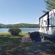 Ground-level photo of an RV parked at a lakeside site with picnic table and lake view — good example of RV pitch and waterfront campsite available at the campground (site gallery/background).