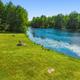 Clear photo of a stocked pond and grassy waterfront area on the property — supports the website text describing a fishing pond and waterfront recreation.