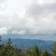 View of mountains and cloudy sky through cabin window.
