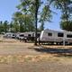 Row of travel trailers on individual pads with small trees and gravel aisles — good overview of typical site spacing and arrangement (gallery page).