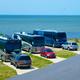 Close view of large RV coaches parked on soundfront pads with water in background — demonstrates waterfront RV accommodations and pad setup visible in the gallery.