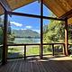Deck with view of boat and floathouse in bay and mountains in background.