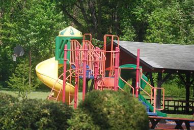 Playground equipment (slides, climbing) and a picnic shelter visible in a landscaped area — from the Facilities page, demonstrates family/recreation facilities on site.