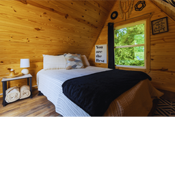 Interior photo of a wood‑lined bedroom inside a cabin — useful to show interior lodging finish and guest experience offered at the ranch.