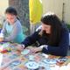 On-site activity photo of people doing arts & crafts at a picnic table — demonstrates campground events/recreation and family-friendly activities (from the campground’s recreation/activities section).