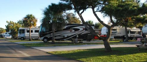 Row of RVs and paved sites with landscaping — clear photo of RV pitches/campsites useful to show available site types. Listed on the site as campground photography.