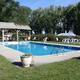 Clear daytime photograph of the on-site swimming pool and surrounding lawn/chairs — matches the 'Campsite' page content and shows a campground amenity.