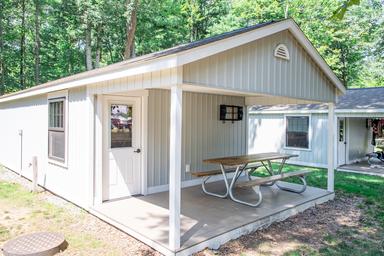 Exterior view of a rustic cabin with covered porch and picnic table — clearly shows the cabin lodging offered (from the cabin rentals gallery).